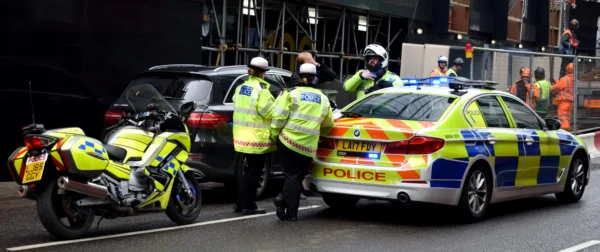 A UK police officer checking a vehicle’s number plate for compliance